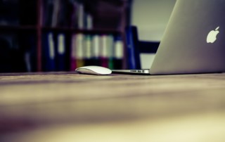 An unoccupied Apple laptop sits on a desktop