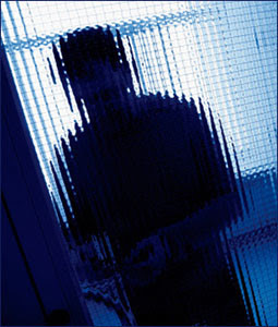 Distorted silhouette of a man seen through textured glass door